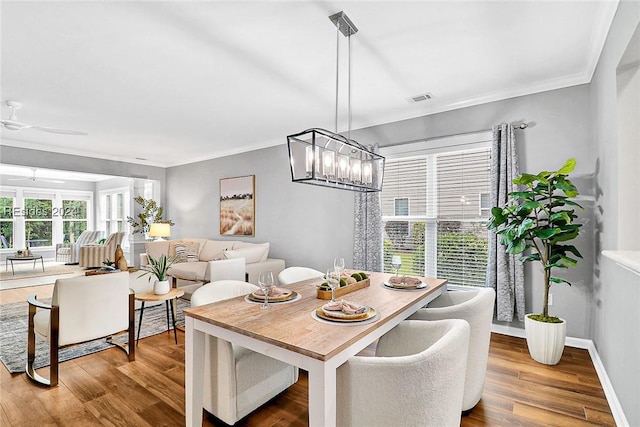 dining area featuring crown molding, hardwood / wood-style floors, and ceiling fan with notable chandelier