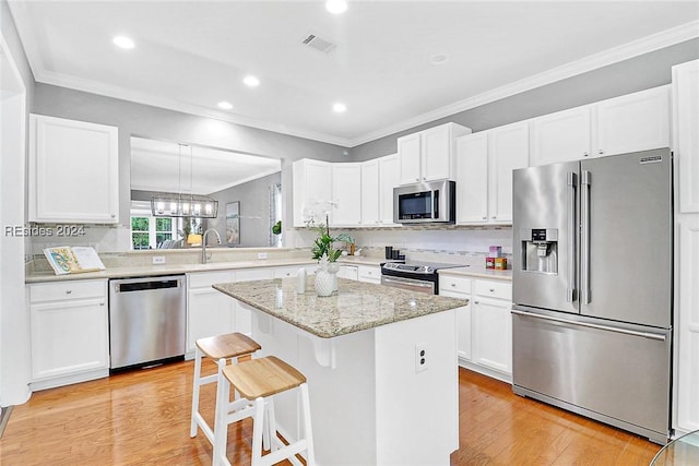 kitchen featuring a kitchen island, tasteful backsplash, white cabinetry, a breakfast bar area, and stainless steel appliances