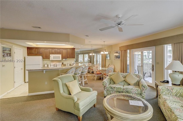 carpeted living room featuring ceiling fan with notable chandelier and a textured ceiling