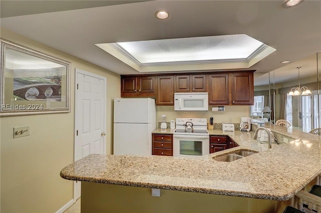 kitchen featuring sink, hanging light fixtures, a tray ceiling, kitchen peninsula, and white appliances