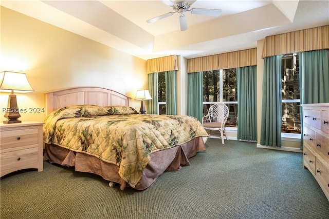 bedroom with ceiling fan, a raised ceiling, and dark colored carpet