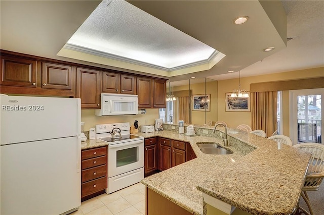 kitchen with sink, a breakfast bar area, white appliances, and a tray ceiling