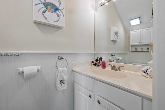 bathroom with lofted ceiling, vanity, and wooden walls