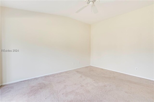 empty room featuring ceiling fan and light carpet