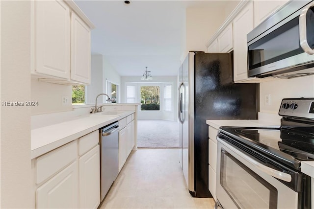 kitchen with lofted ceiling, sink, white cabinets, light colored carpet, and stainless steel appliances