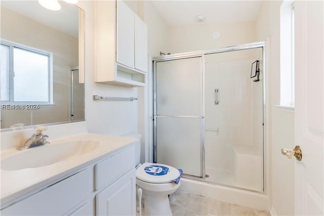 bathroom featuring tile patterned floors, vanity, toilet, and a shower with shower door