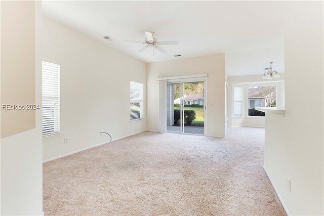 carpeted empty room with ceiling fan with notable chandelier