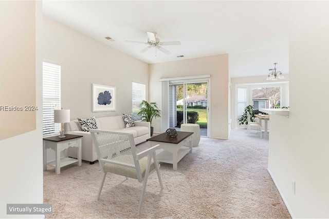 carpeted living room featuring ceiling fan with notable chandelier