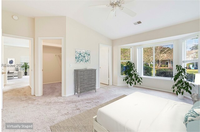 bedroom with ceiling fan, lofted ceiling, light carpet, and a walk in closet