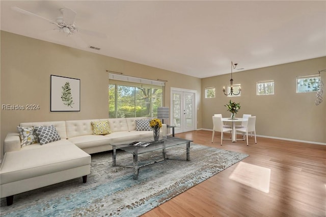 living room featuring hardwood / wood-style flooring, ceiling fan with notable chandelier, and french doors