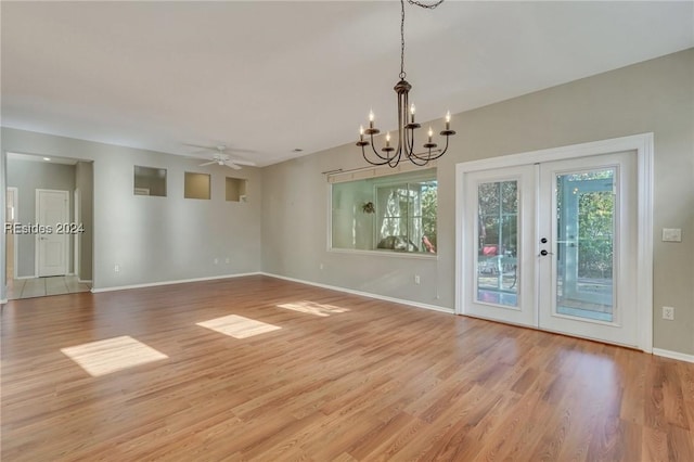 unfurnished room featuring ceiling fan with notable chandelier and light wood-type flooring