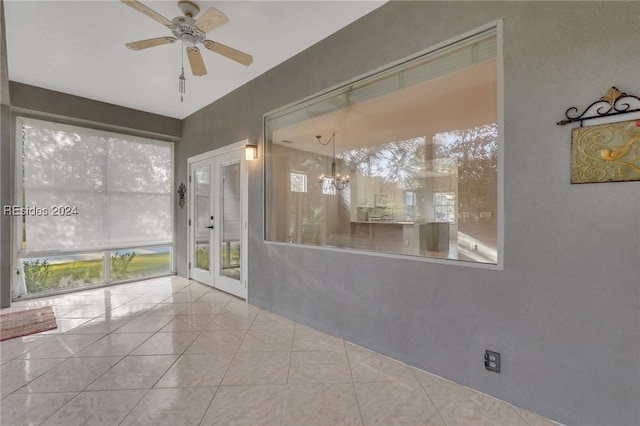 unfurnished sunroom with ceiling fan with notable chandelier