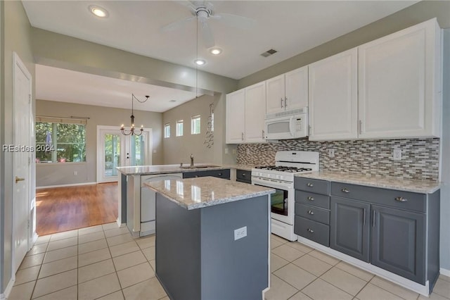 kitchen featuring white cabinetry, light stone counters, kitchen peninsula, pendant lighting, and white appliances