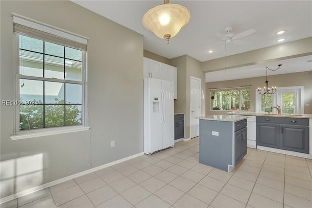 kitchen featuring white appliances, gray cabinets, hanging light fixtures, plenty of natural light, and a center island