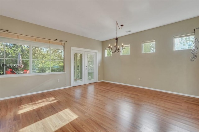 spare room featuring hardwood / wood-style floors, a notable chandelier, and french doors