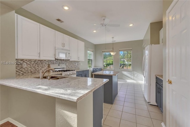 kitchen featuring decorative light fixtures, kitchen peninsula, white appliances, light stone countertops, and white cabinets