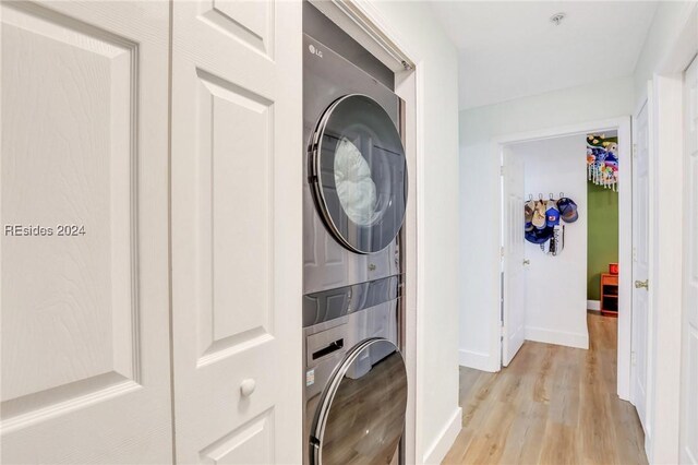 laundry area featuring stacked washer and dryer and light hardwood / wood-style flooring