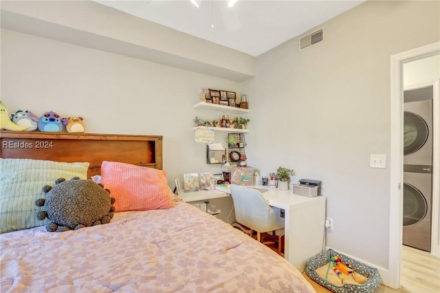 bedroom featuring ceiling fan, stacked washing maching and dryer, and light hardwood / wood-style flooring