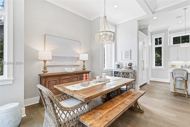 dining space with beam ceiling, wood-type flooring, a notable chandelier, and crown molding