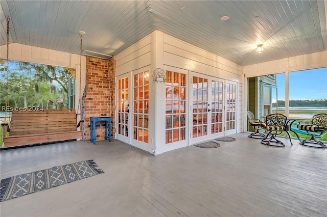 sunroom / solarium featuring a water view, wood ceiling, and french doors