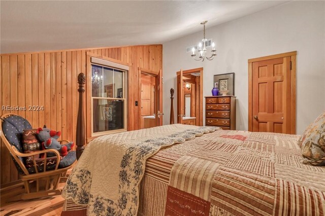 bedroom with wooden walls and a chandelier