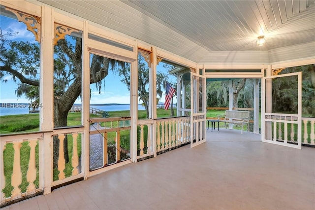 unfurnished sunroom featuring vaulted ceiling and a water view