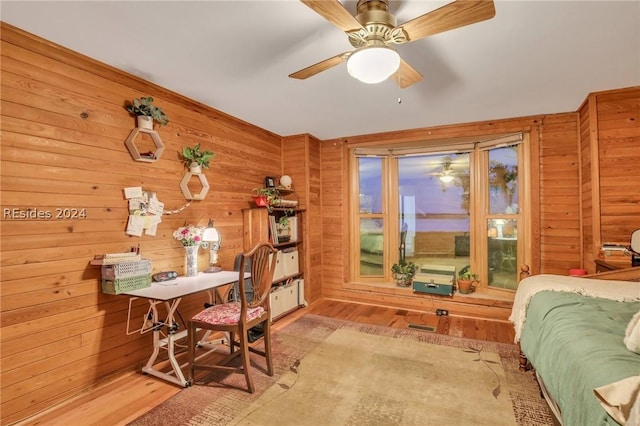 interior space with wooden walls, ceiling fan, and light wood-type flooring