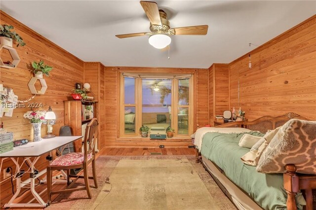 bedroom with ceiling fan and wooden walls