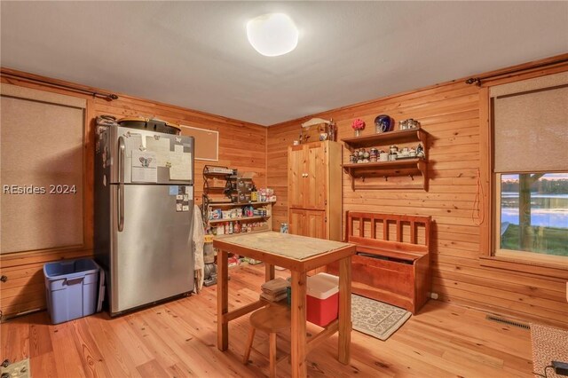 kitchen featuring wooden walls, stainless steel refrigerator, and light hardwood / wood-style flooring