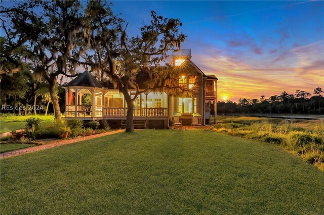 exterior space featuring a gazebo, a wooden deck, and a lawn