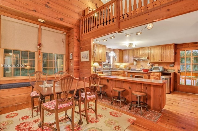 dining space with sink, light hardwood / wood-style flooring, and wood walls