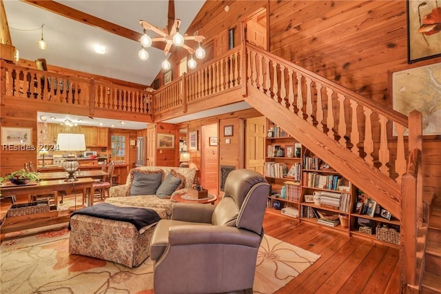 living room with high vaulted ceiling, wood walls, beamed ceiling, wood-type flooring, and a notable chandelier