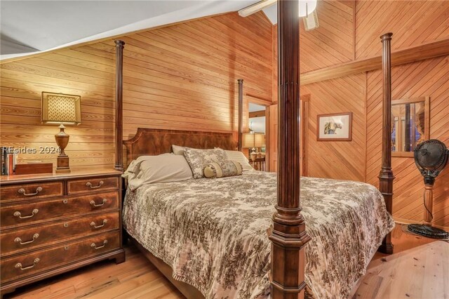 bedroom with ceiling fan, wooden walls, and light hardwood / wood-style flooring