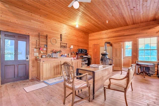 dining area featuring ceiling fan, wooden ceiling, wooden walls, and light hardwood / wood-style floors