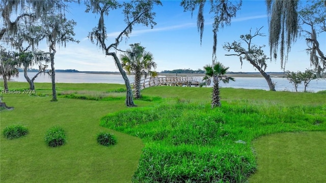 surrounding community with a water view and a yard