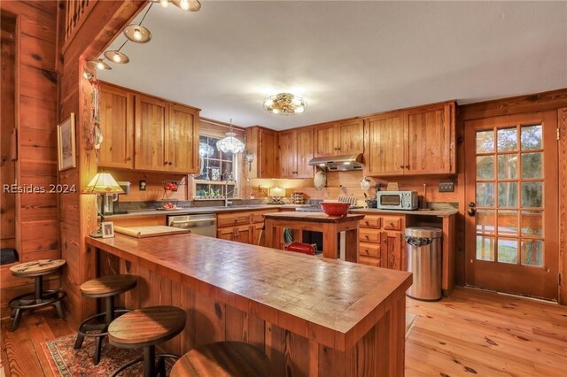 kitchen featuring a kitchen bar, sink, kitchen peninsula, stainless steel appliances, and light hardwood / wood-style floors