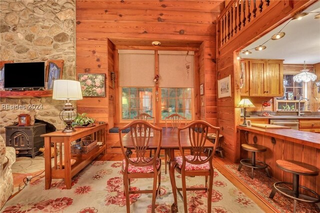 dining room featuring light hardwood / wood-style flooring, wood walls, and a wood stove