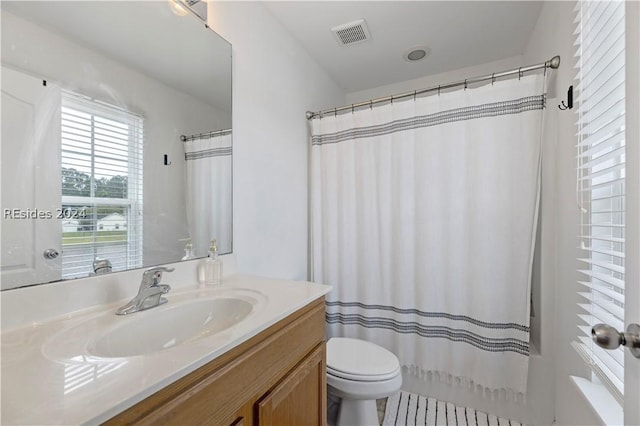 bathroom featuring vanity, toilet, and walk in shower