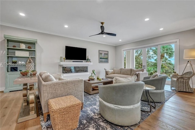 living room featuring crown molding, ceiling fan, and light hardwood / wood-style flooring