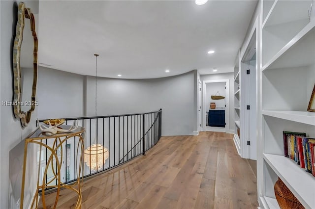 corridor with built in shelves and light hardwood / wood-style floors