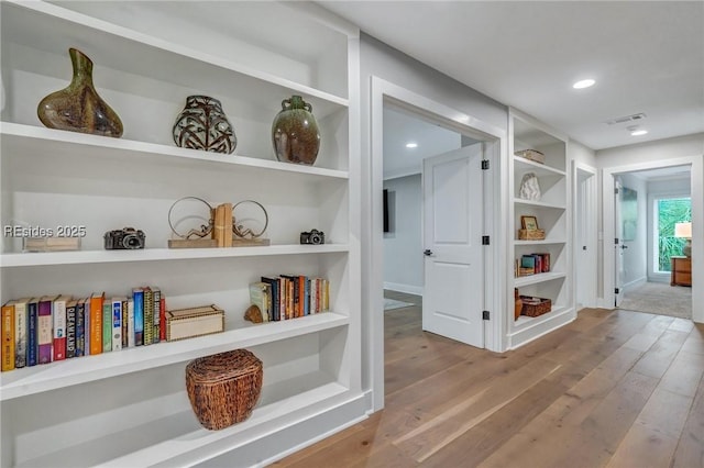 hallway featuring built in shelves and light hardwood / wood-style flooring