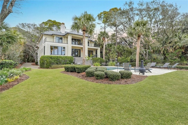 rear view of property featuring a balcony, a yard, and a patio