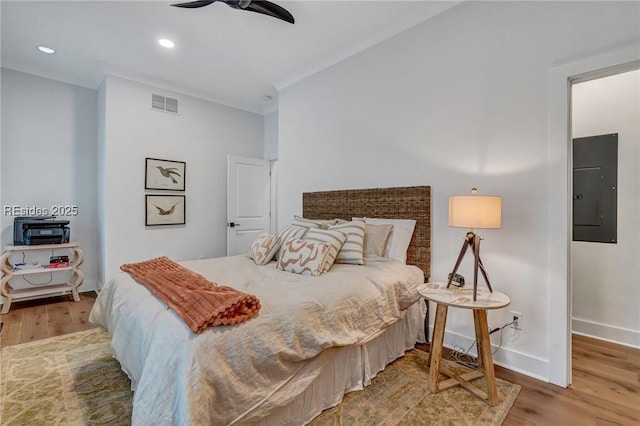 bedroom featuring ceiling fan, electric panel, and hardwood / wood-style floors