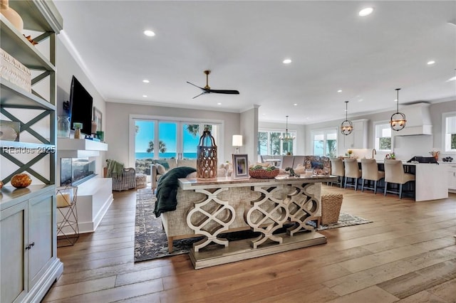 living room with crown molding, wood-type flooring, and ceiling fan with notable chandelier