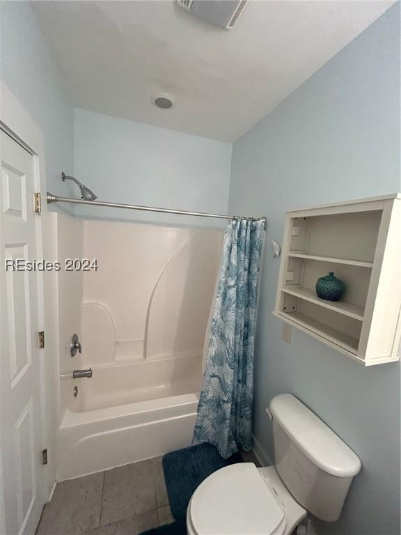 bathroom featuring tile patterned flooring, shower / bath combination with curtain, and toilet