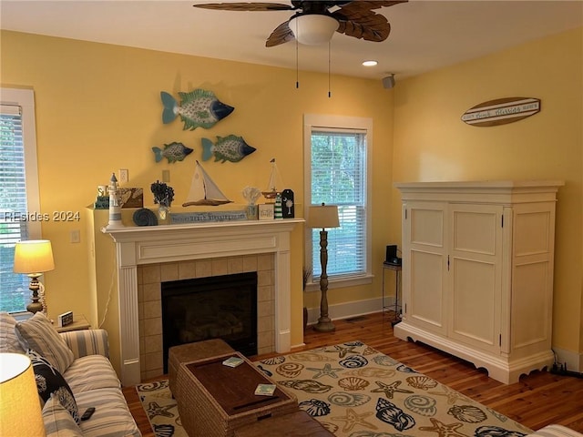 living area with dark hardwood / wood-style flooring, a tile fireplace, and ceiling fan