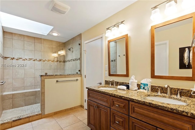 bathroom with vanity, a skylight, tile patterned flooring, and a tile shower