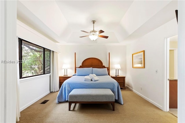 carpeted bedroom with ceiling fan and a tray ceiling