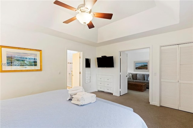 carpeted bedroom with a raised ceiling and ceiling fan