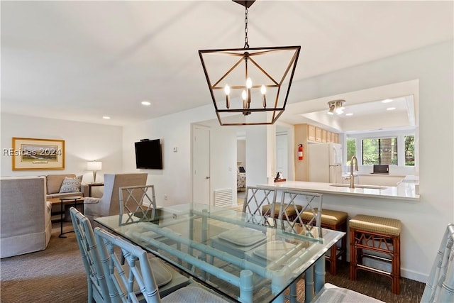 carpeted dining area featuring sink and a chandelier